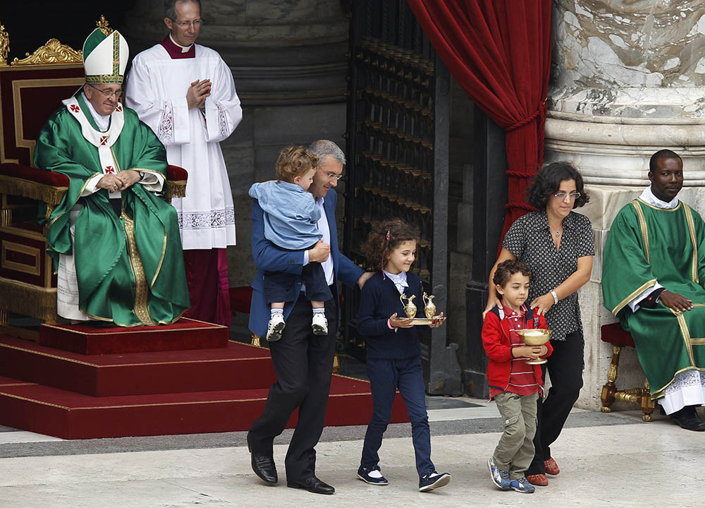 Pope Francis watches as a family carries offertory gifts to the altar during a Mass for catechists in St. Peter's Square at the Vatican in September 2013. (CNS photo/Paul Haring)