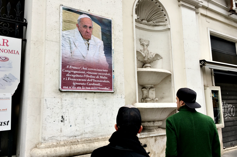 People look at a poster expressing criticism of Pope Francis in Rome Feb. 5, 2017. Numerous copies of the poster were placed in the center of Rome but were quickly covered or removed by city authorities. (CNS/Paul Haring)