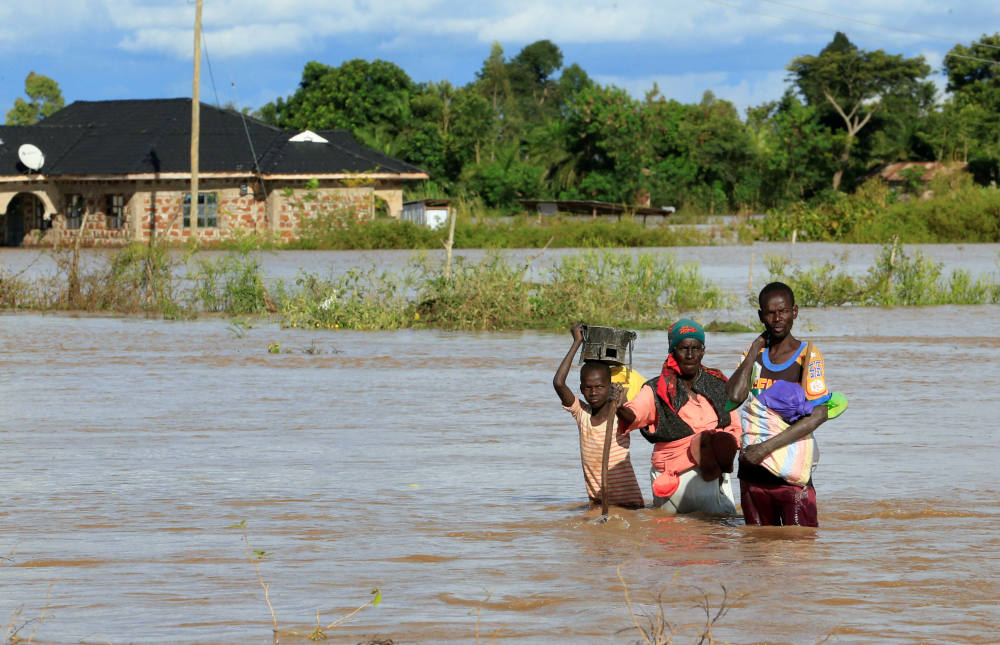 A boy and young man help a woman wade through floodwaters in Busia, Kenya, May 3, 2020. Some African Catholic advocates believe the church needs to do more to advance the ideas in Pope Francis' 2015 encyclical, "Laudato Si'." (CNS photo/Thomas Mukoya, Reu