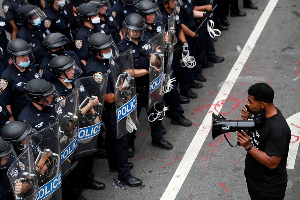 A demonstrator with Black Lives Matter stands in front of police officers in New York City inside of an area called the "City Hall Autonomous Zone" July 1. (CNS/Reuters/Andrew Kelly)