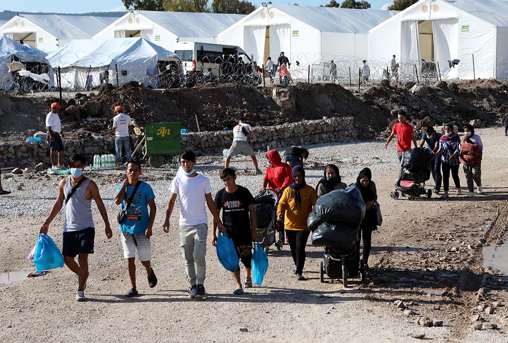 Migrants walk with their belongings as they make their way to the Kara Tepe refugee camp on the Greek island of Lesbos Oct. 14, 2020. (CNS/Reuters/Elias Marcou)