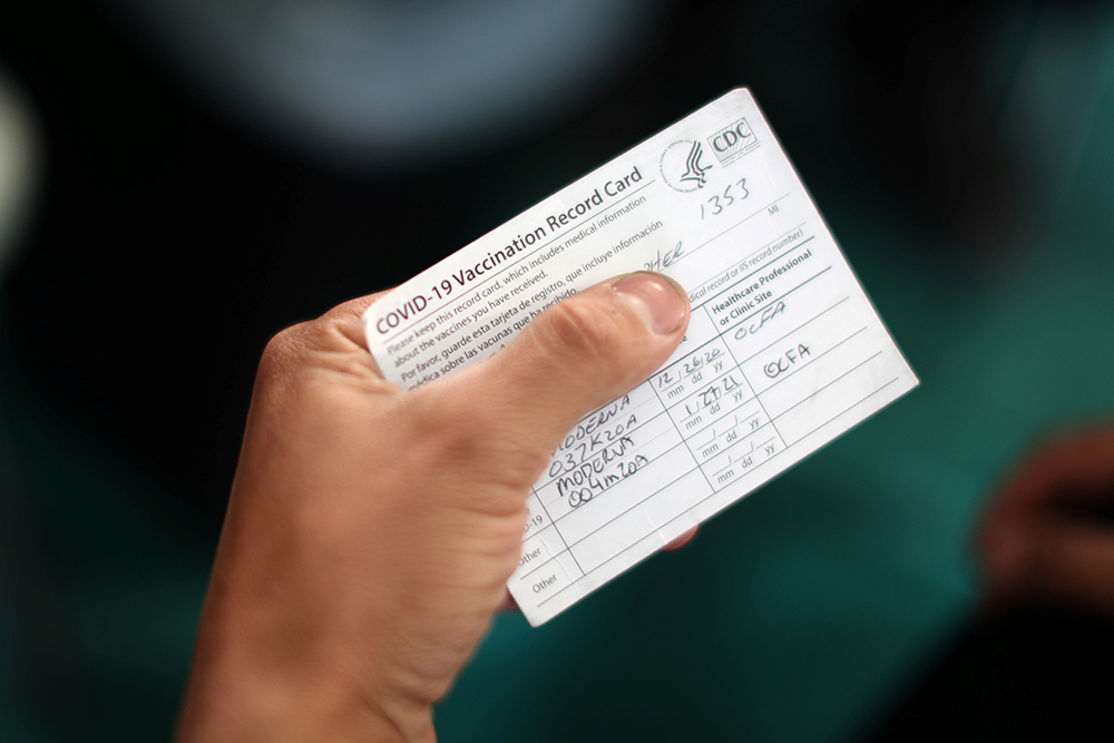 An Orange County firefighter in Irvine, California, holds his vaccination card after receiving the coronavirus vaccine Jan. 27. (CNS/Reuters/Lucy Nicholson)