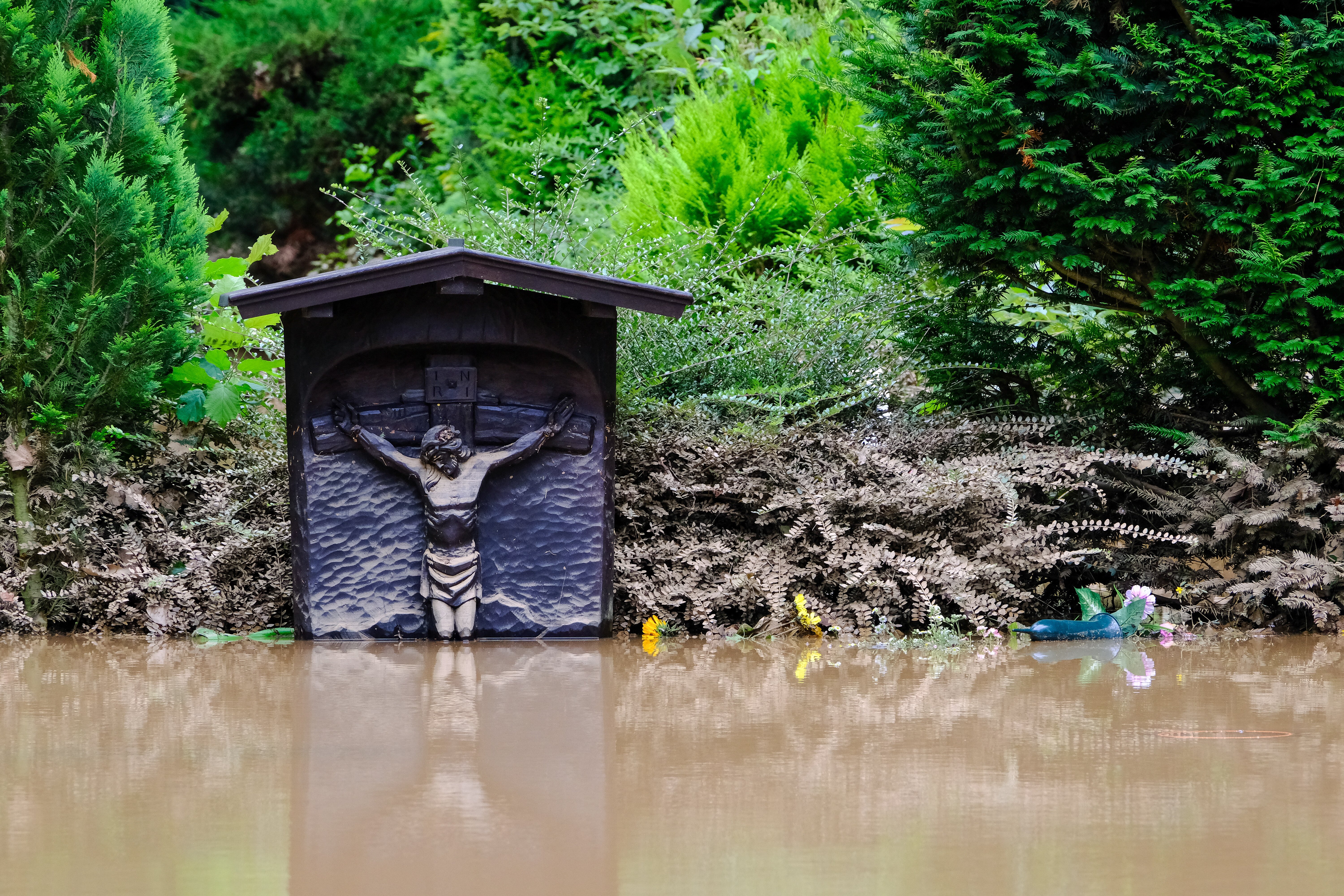 A grave marker is surrounded by floodwaters at a cemetery in Erftstadt, Germany, July 16, 2021. Aid agencies in developing countries more accustomed to dealing with natural disasters have offered words of compassion and concern in response to Germany's di