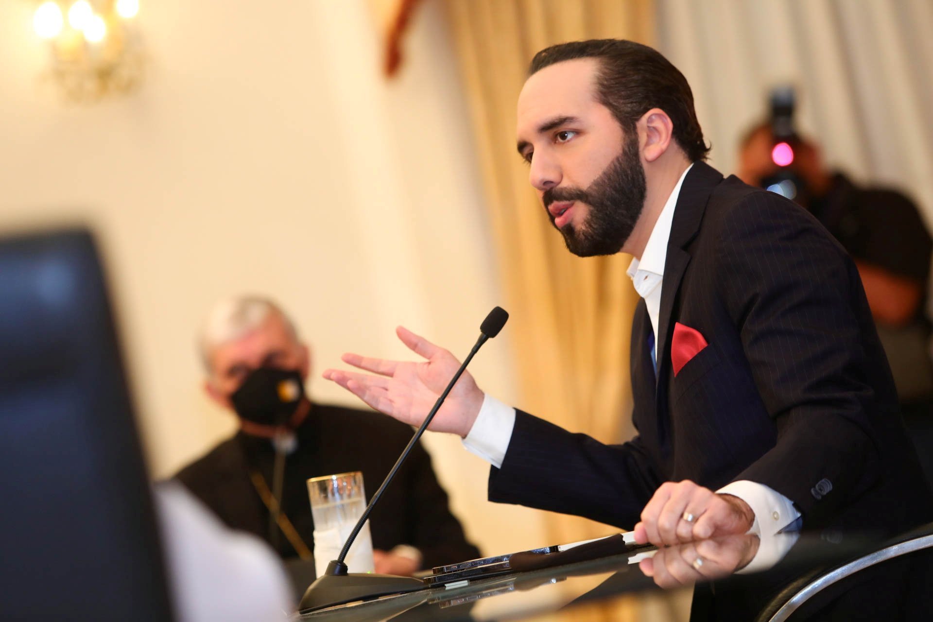 A prelate wearing a protective mask looks on as Salvadoran President Nayib Bukele takes part in a meeting at the Presidential House in San Salvador May 3, 2021. Without naming the president, the bishops said Sept. 12 that making changes without following 