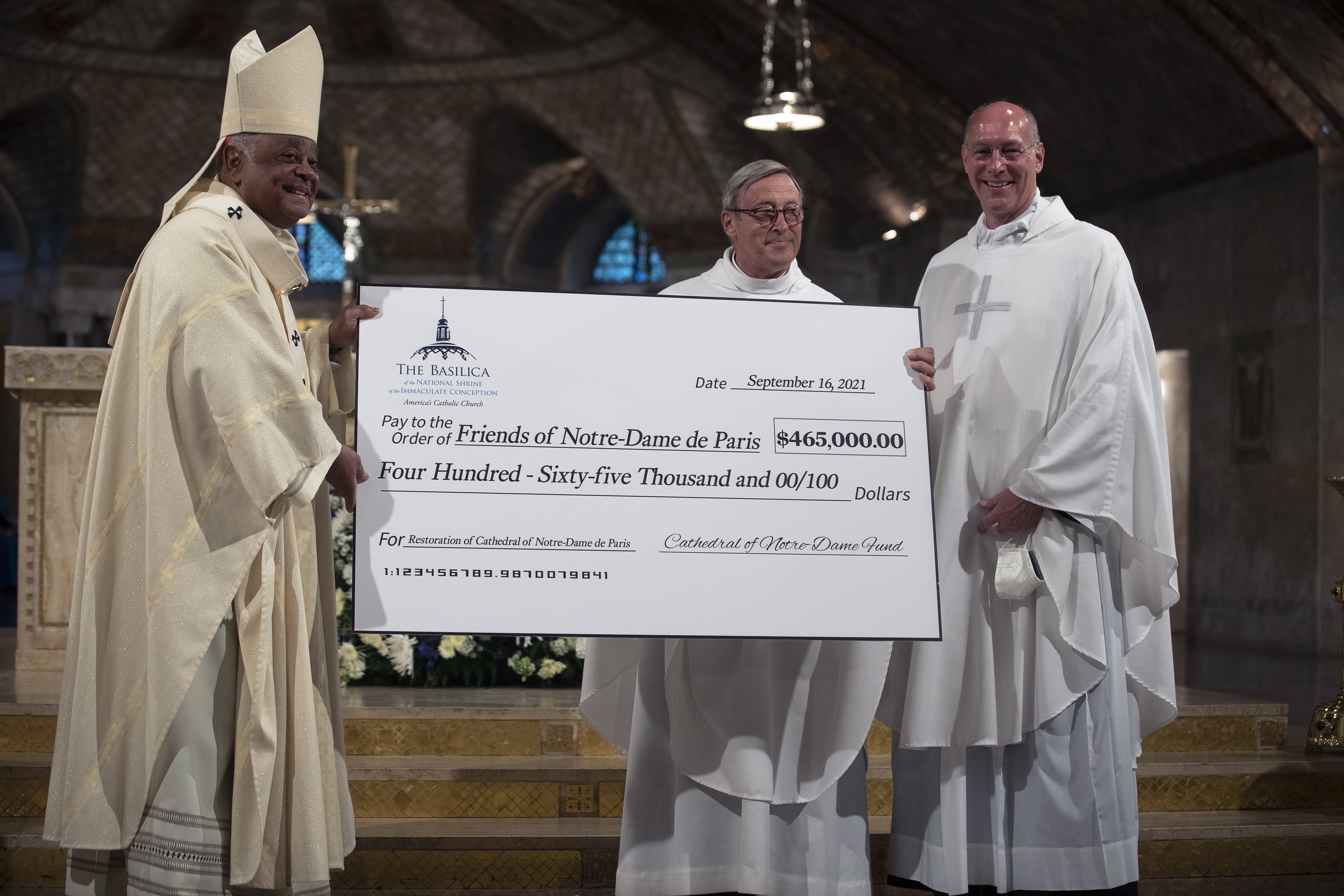 Msgr. Patrick Chauvet, center, rector of the Notre Dame Cathedral in Paris, receives a check from Msgr. Walter Rossi, rector of the Basilica of the National Shrine of the Immaculate Conception in Washington, and Washington Cardinal Wilton D. Gregory after