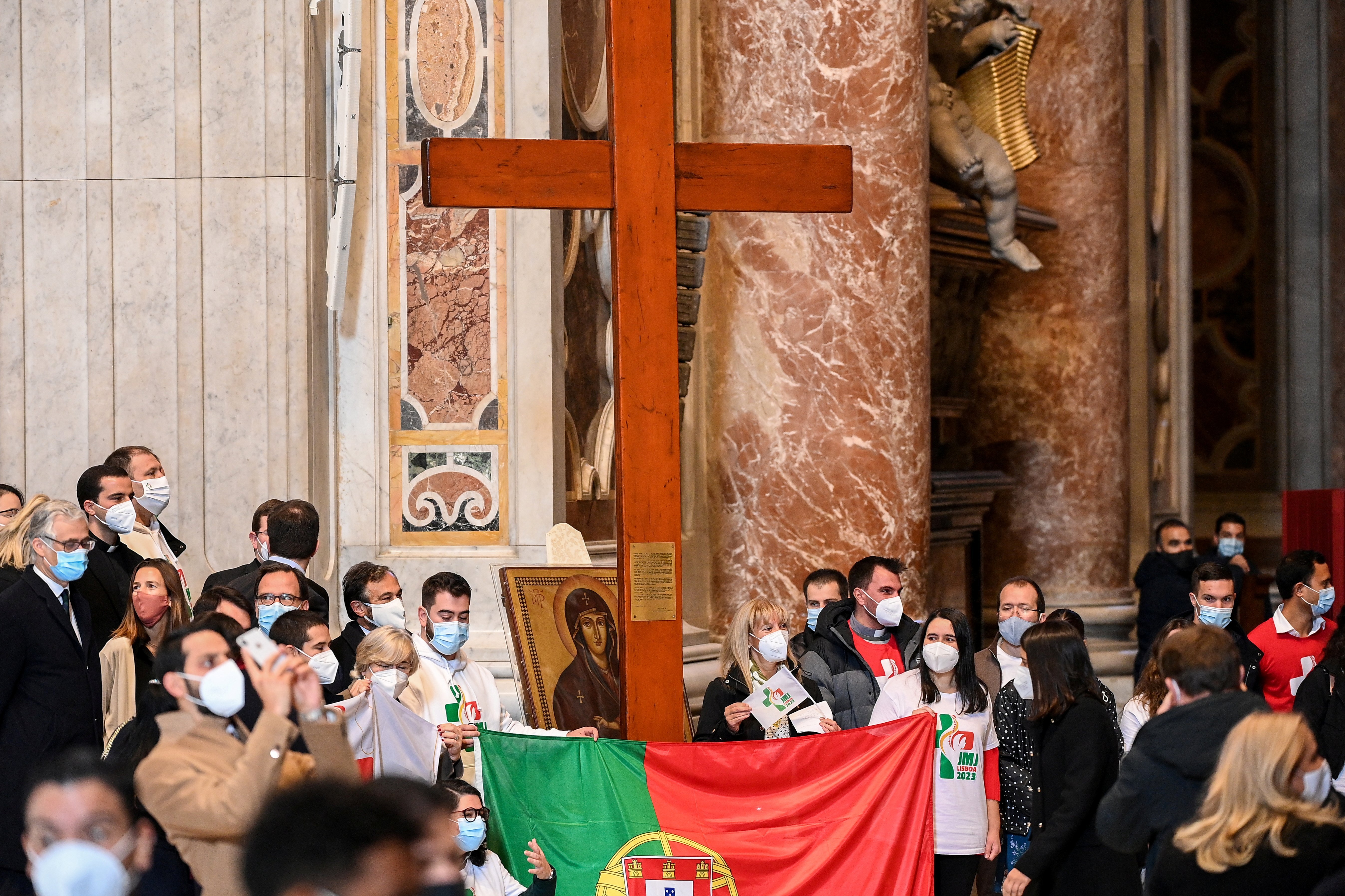 Young people from Portugal are pictured with the World Youth Day cross and their country's national flag following the cross' handover from their Panamanian peers at the end of Pope Francis' Mass Nov. 22, 2020. (CNS photo/Vincenzo Pinto, Reuters pool)