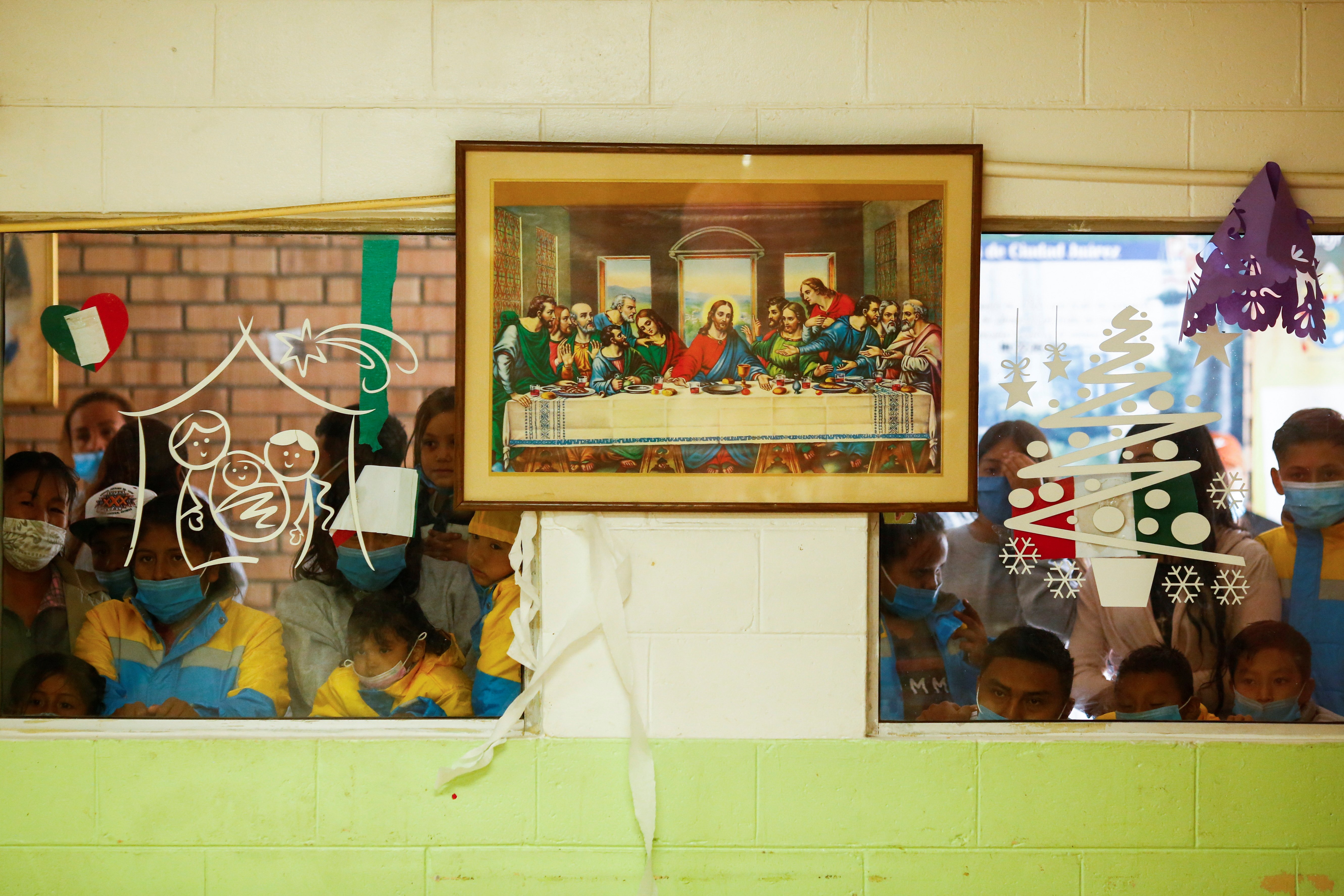 Migrants who were returned to Mexico under Title 42, a public health code provision, after seeking asylum in the U.S. observe a quinceañera celebration through a window at the Casa del Migrante shelter in Ciudad Juarez, Mexico, Sept. 30, 2021. (CNS photo/