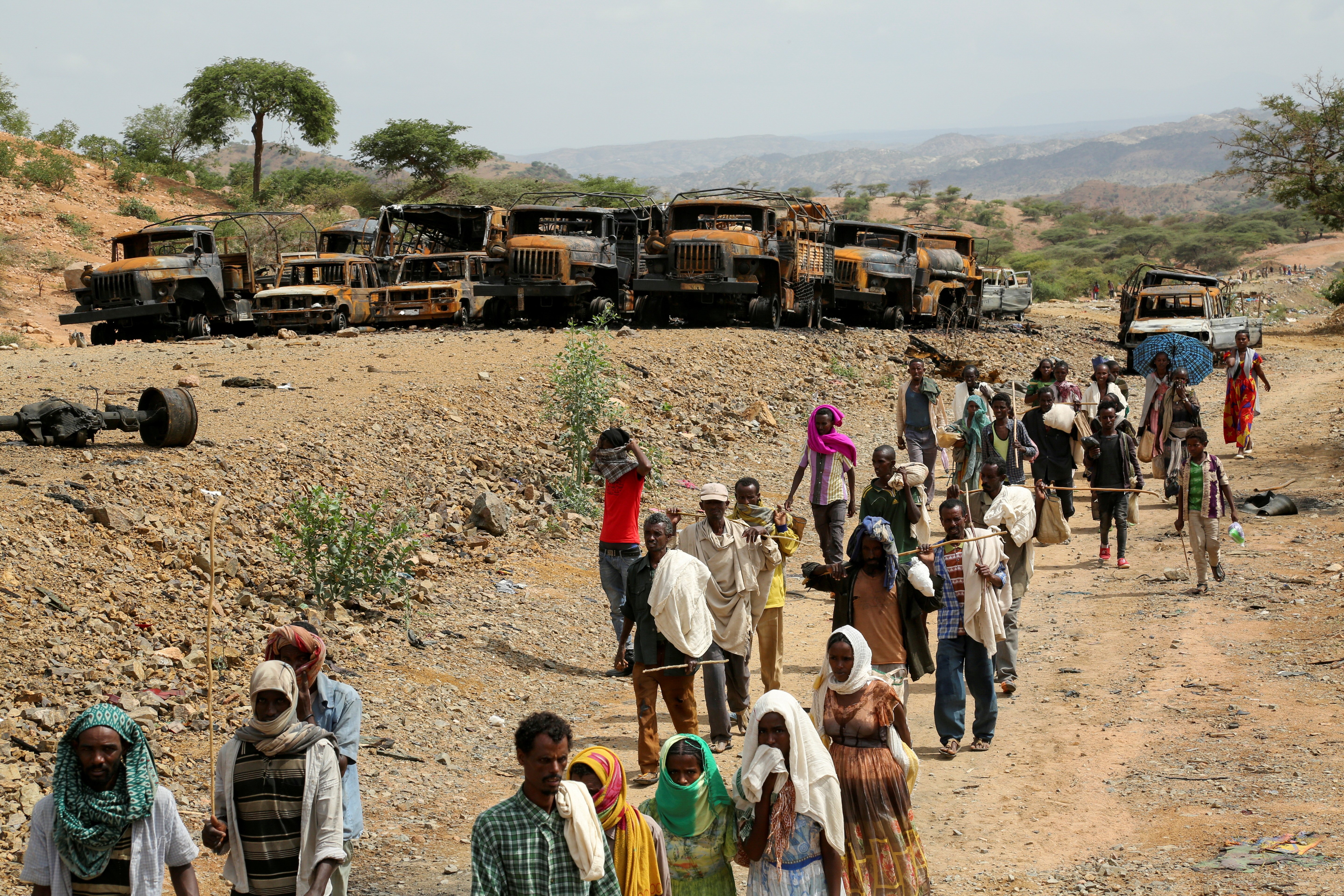 Villagers returning from a market in the town of Yechila walk past scores of burned vehicles in Ethiopia's Tigray region July 10, 2021. (CNS photo/Giulia Paravicini, Reuters)