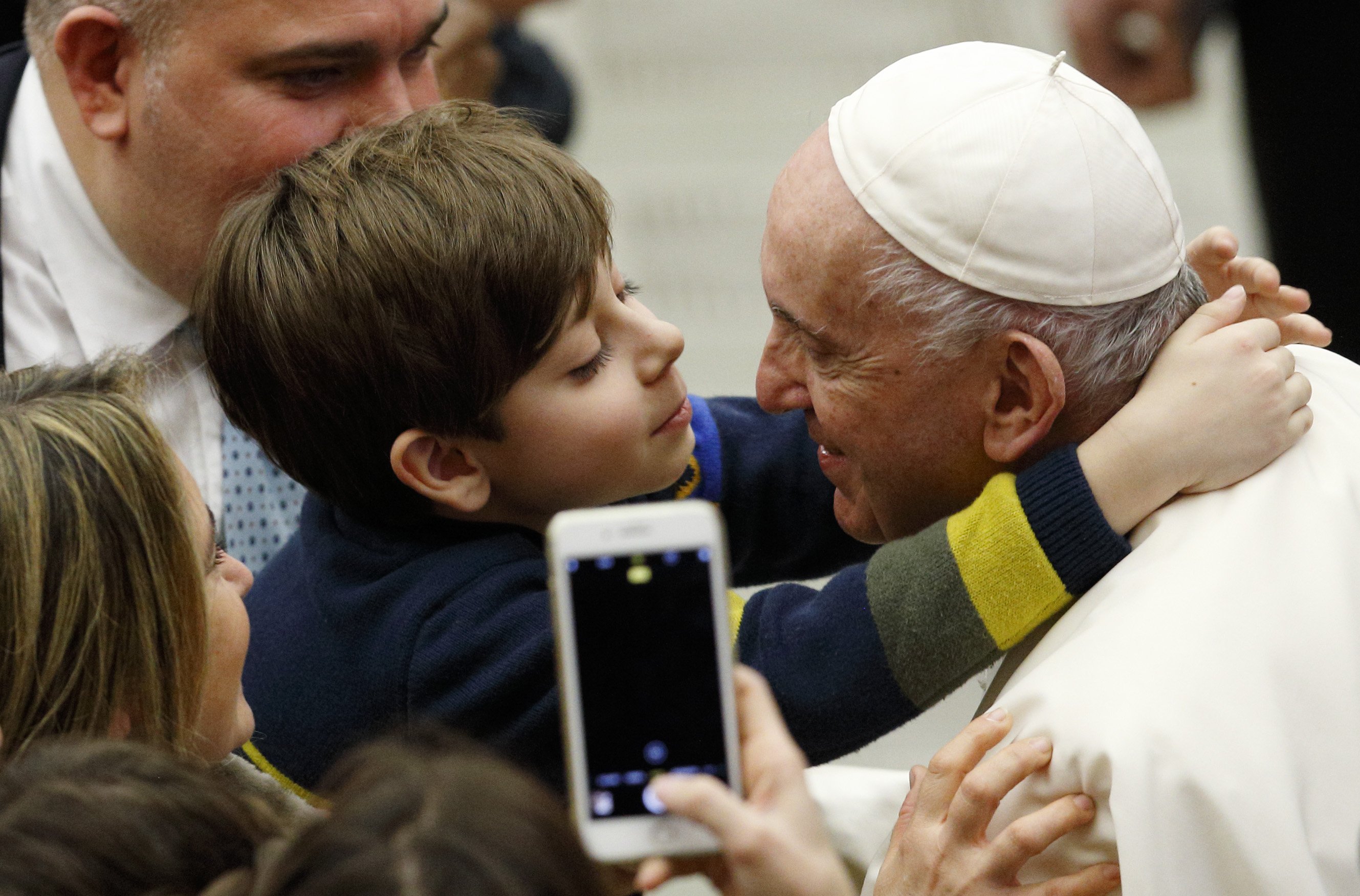 A boy embraces Pope Francis during his general audience in the Paul VI hall at the Vatican Dec. 15, 2021. (CNS photo/Paul Haring)