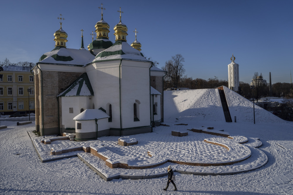 A woman walks past a snow-covered church courtyard in Kyiv, Ukraine, Thursday, Dec. 1, 2022. (AP Photo/Bernat Armangue)