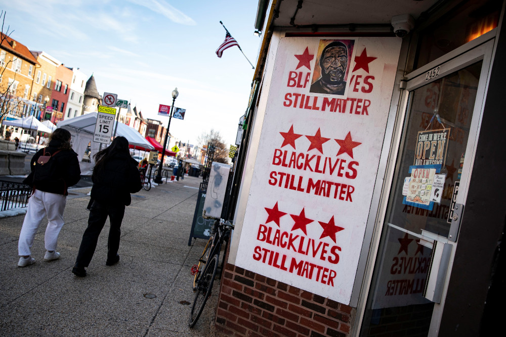 People in Washington walk past a sign about the Black Lives Matter movement Feb. 21, 2021. (CNS/Reuters/Al Drago)