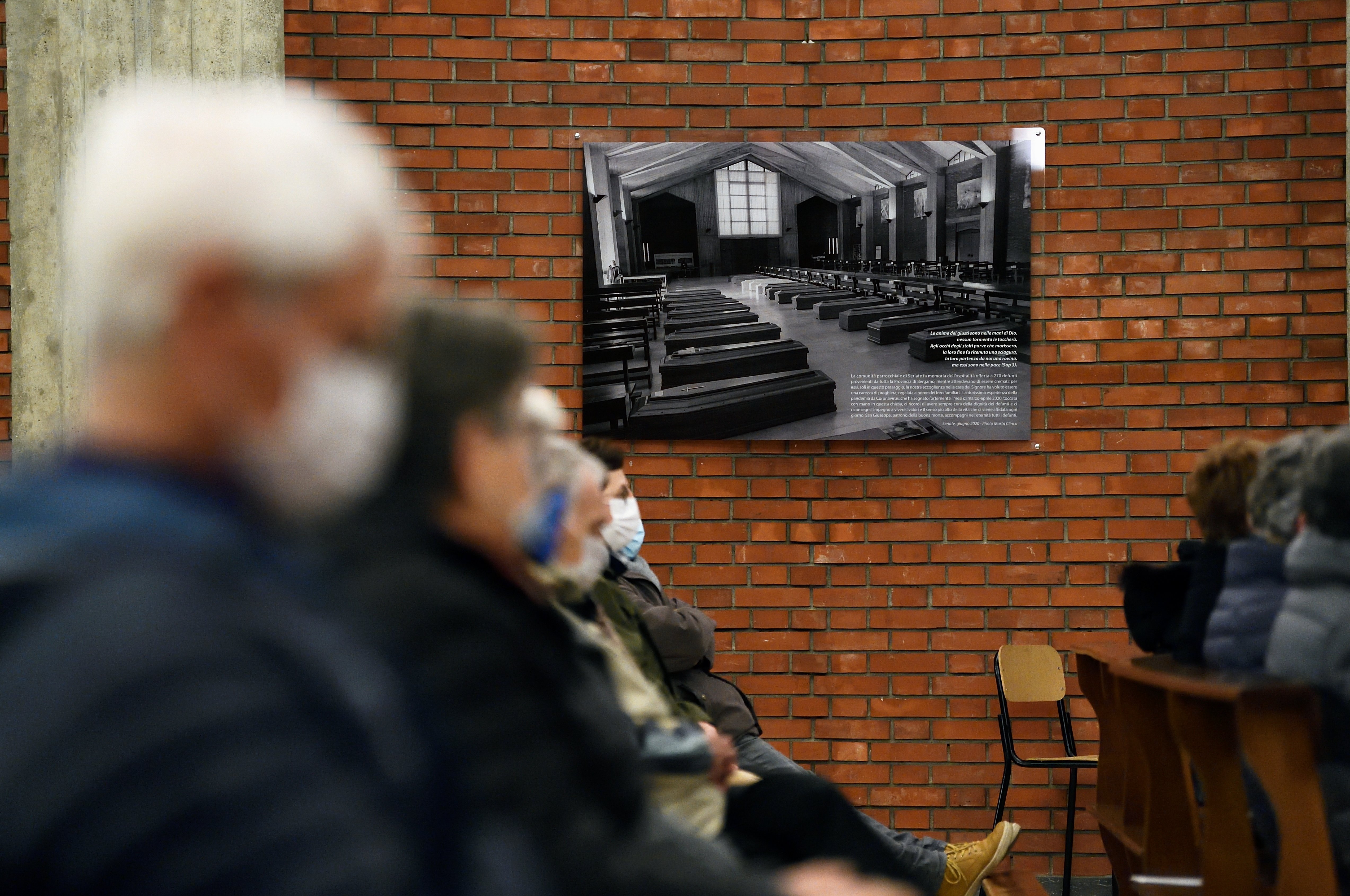 A black and white picture from March 2020 showing coffins piled up inside the church of San Giuseppe is seen on the wall of that church in Seriate, Italy, in this Feb. 28, 2021, file photo. (CNS photo/Flavio Lo Scalzo, Reuters)