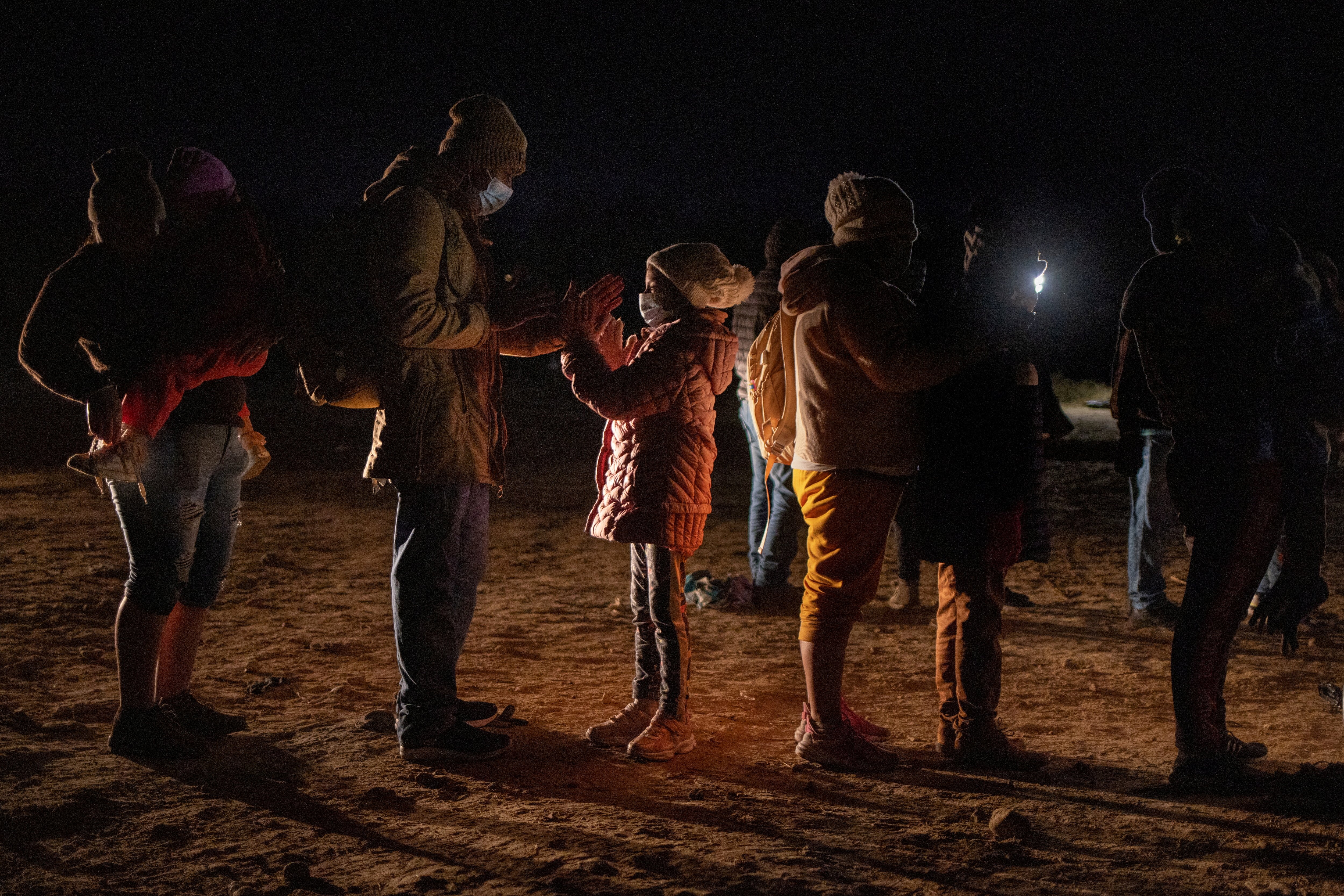 Romando, a migrant from Peru seeking asylum in the United States, plays a hand-clapping game with his daughter Alexa, 7, as they stand in line waiting to be processed in Roma, Texas, Feb. 28, 2022. (CNS photo/Adrees Latif, Reuters)