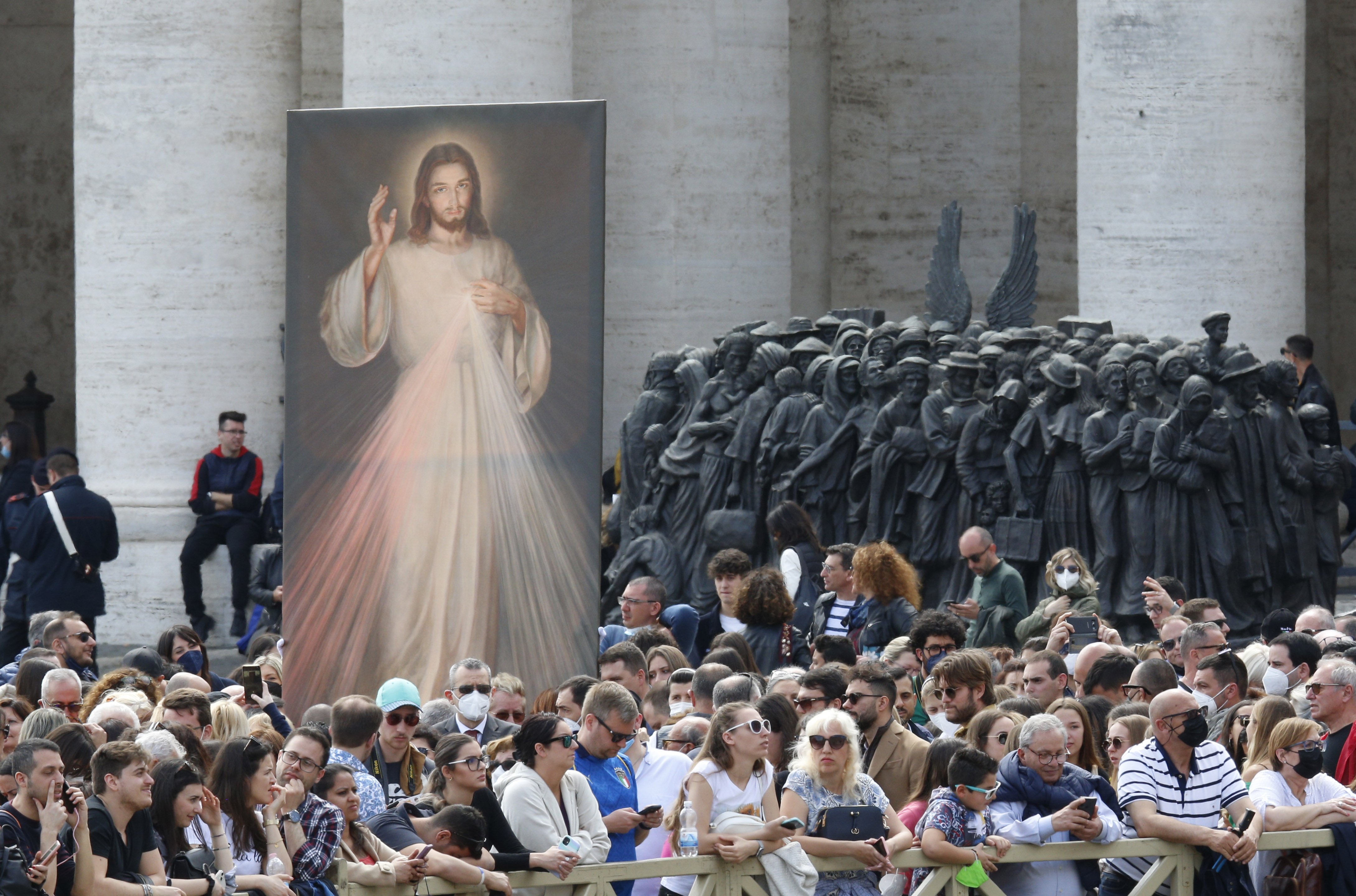 An image of Jesus of Divine Mercy and the "Angels Unawares" sculpture are seen in St. Peter's Square as people wait for Pope Francis to lead the "Regina Coeli" at the Vatican April 24, 2022. (CNS photo/Paul Haring)