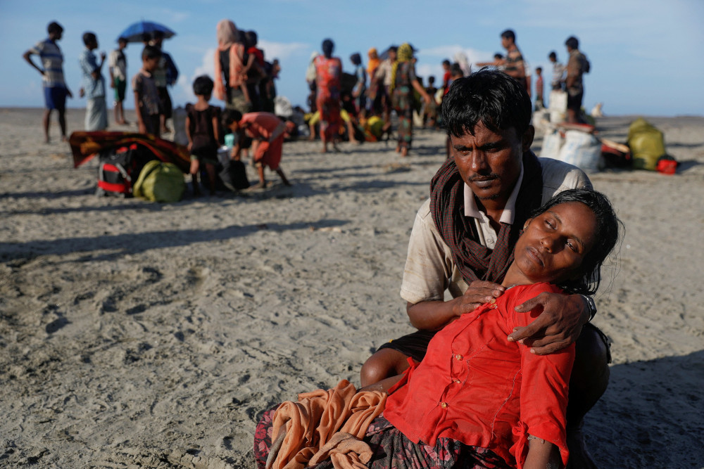 A man who said his village was burned and relatives killed by Myanmar soldiers comforts his wife as Rohingya refugees arrive by a wooden boat from Myanmar in Shah Porir Dwip, Bangladesh, Oct. 1, 2017. 