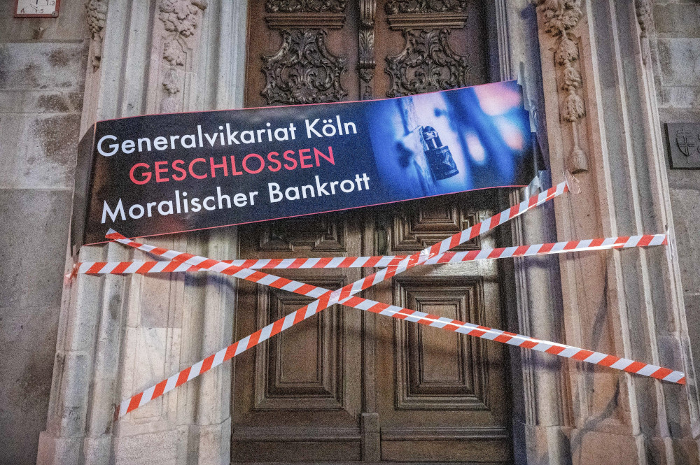 A banner with the inscription "Generalvikariat Köln — Geschlossen — Moralischer Bankrott" ("Vicar General's office Cologne CLOSED. Moral bankruptcy") and barrier tape are pictured stretched over the archdiocesan office in Cologne, Germany, Aug. 15.