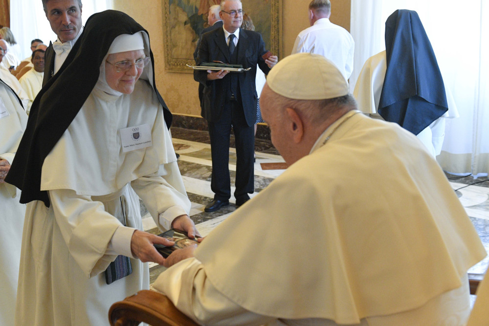 Pope Francis accepts a book from Sister Mary Norbert Loushin during an audience with the Canons Regular of Prémontré, commonly known as the Norbertines, at the Vatican Sept. 22, 2022.