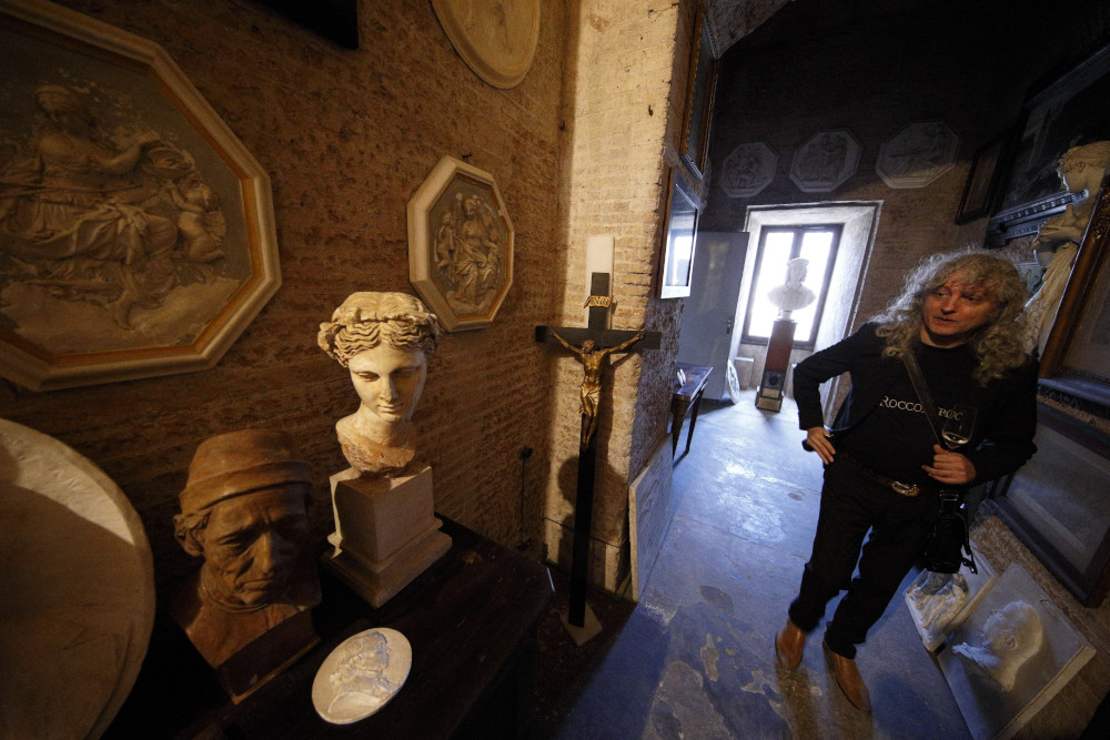 A person stands in a dim stone hall with Roman stone sculptures