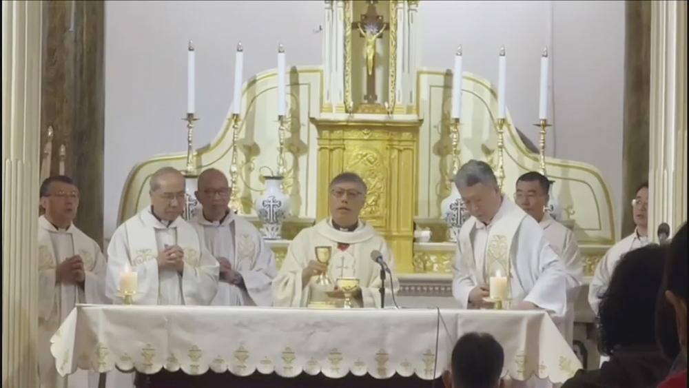 A group of priests wearing white vestments stands behind an altar covered in a white cloth