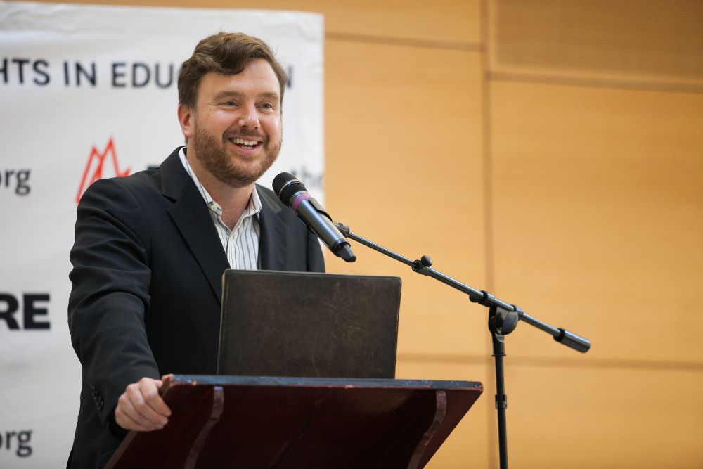 Greg Lukianoff stands at a lectern and speaks into a microphone.