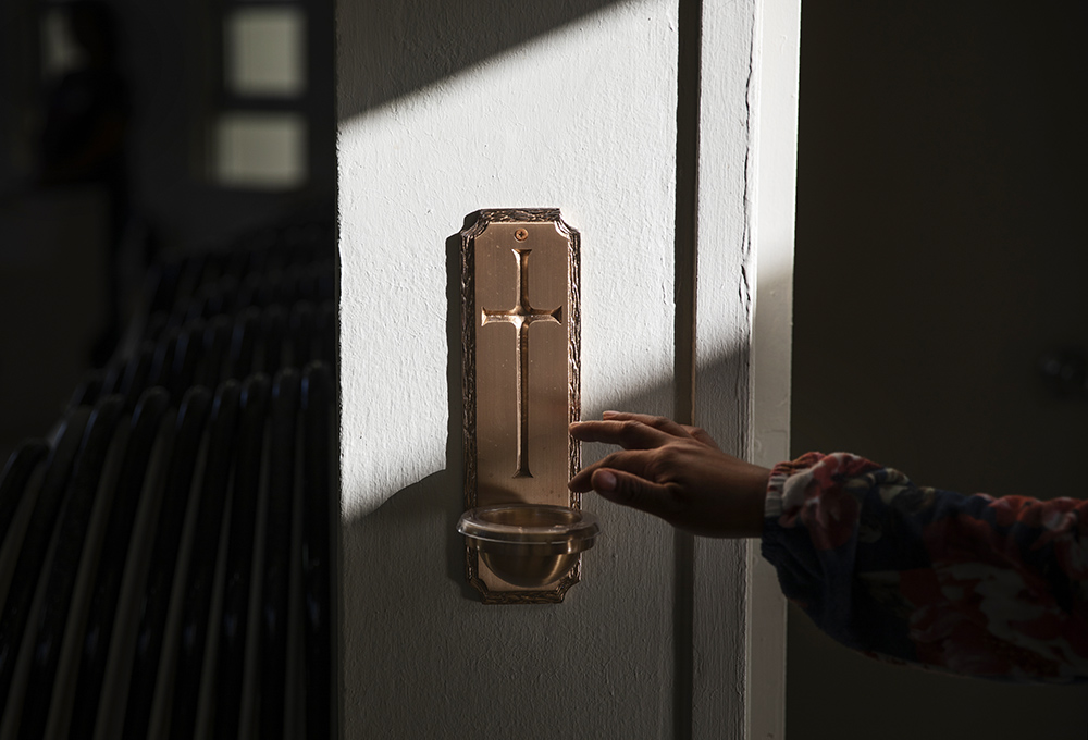 A parishioner reaches for holy water upon entering for Mass at Our Lady of Purification Catholic Church in Maina, Guam, May 10, 2019. (AP/David Goldman)