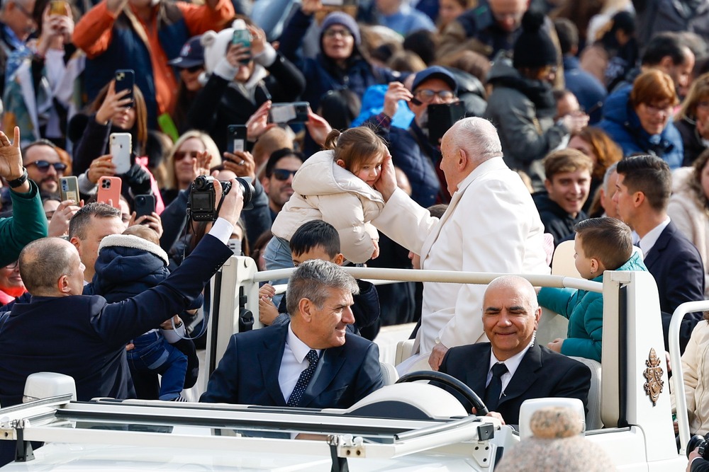 Pope Francis greets child during general audience. 