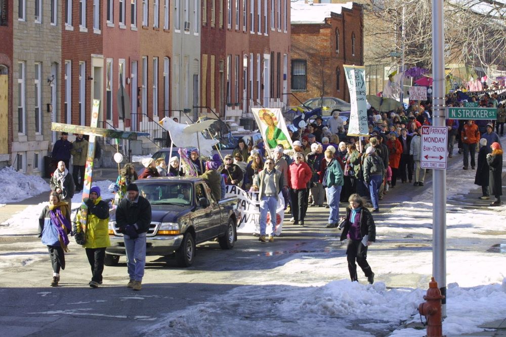 A pickup truck carrying the casket of peace activist Philip Berrigan makes its way down a west Baltimore street during his funeral procession Dec. 9, 2002.