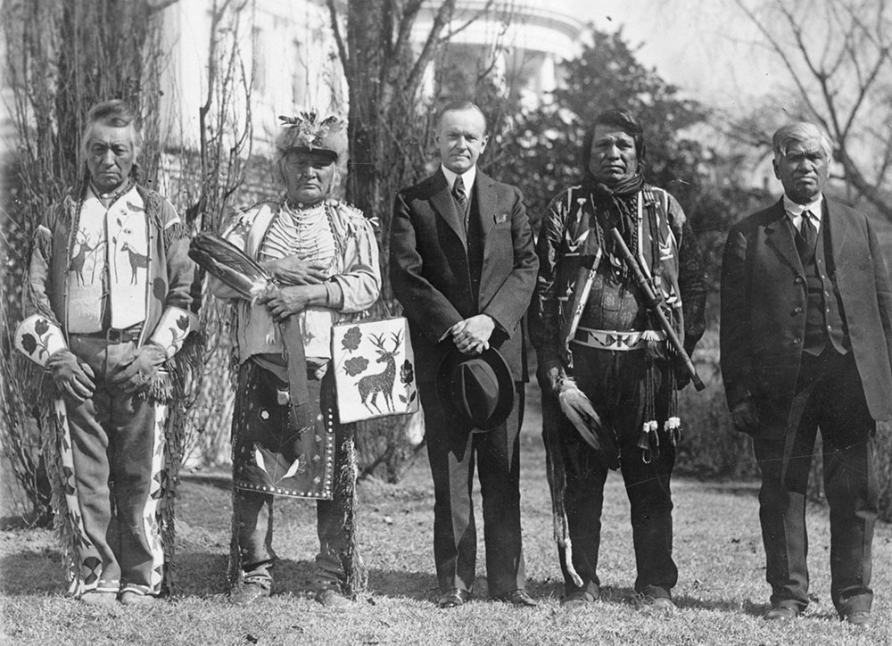 President Calvin Coolidge stands outside the White House with four Osage leaders after signing the Indian Citizenship Act. (Wikimedia Commons/National Photo Company Collection)
