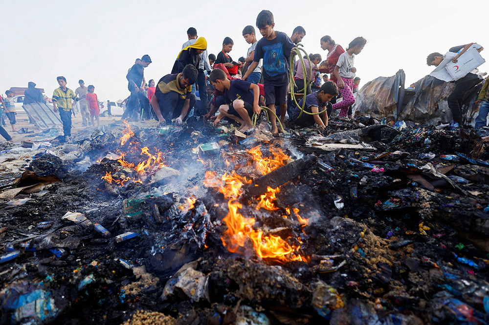 Palestinians search for food among burned debris May 27, 2024, in the aftermath of an Israeli airstrike on an area designated for displaced people in Rafah, in the southern Gaza Strip. (OSV News/Reuters/Mohammed Salem)