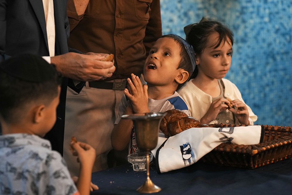 Jewish children eat pieces of challah bread after the prayer was recited during a Shabbat service at the Beth Shalom synagogue, in Havana, Cuba, Friday, Feb. 16, 2024. Jews are believed to have arrived to Cuba with Christopher Columbus in 1492, but the Cuban community officially began in the early 20th century, said the vice president of Cuba's Hebrew Community. (AP/Ramon Espinosa)