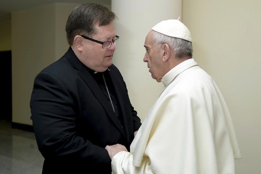 Pope Francis faces Cardinal La Croix, with hand on arm, in conversation. 