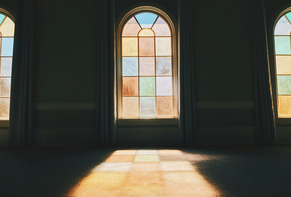 Light shining through a rainbow-colored stained glass window (Unsplash/Daniel McCullough)