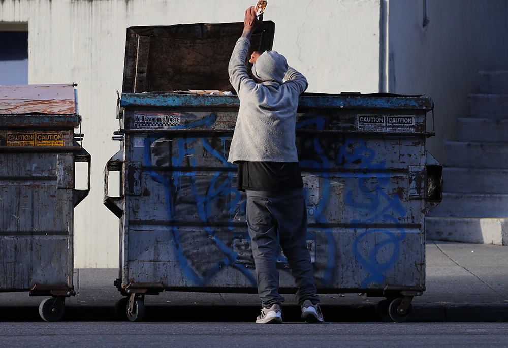 A man pulls food out of a dumpster May 19 in San Francisco. (OSV News/Bob Roller)