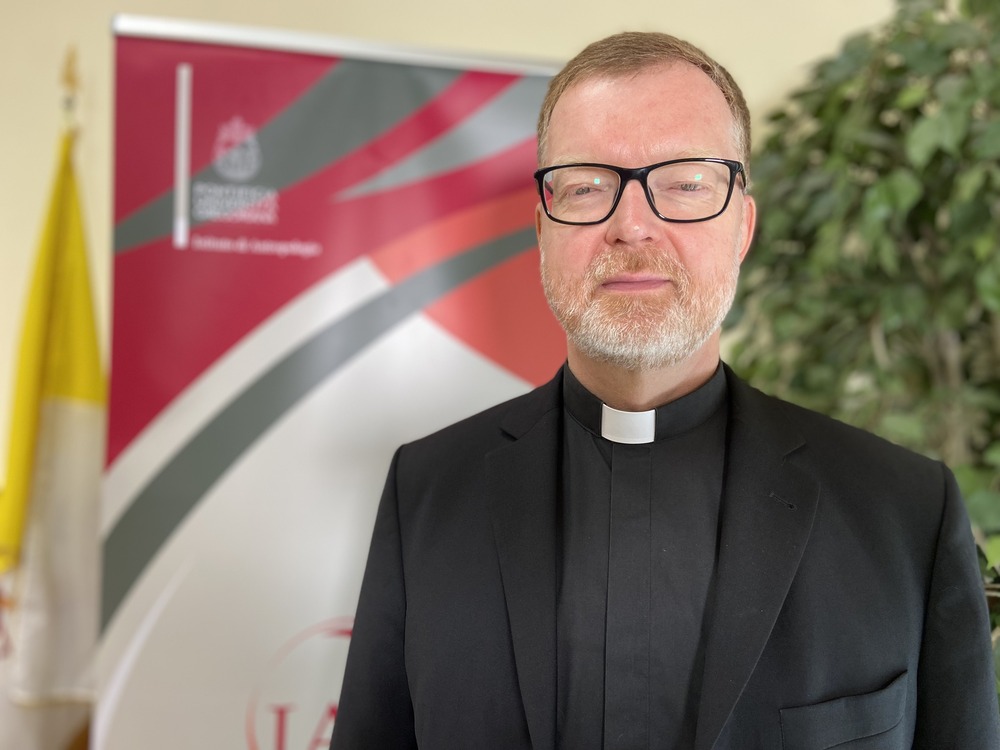 Father Zollner poses in front of an event banner. 