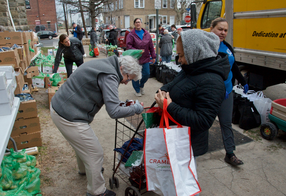 Volunteers fill bags and carts with food during the SSJ Neighborhood Center's monthly food distribution day, March 20 in Camden, New Jersey. (GSR photo/Dan Stockman)