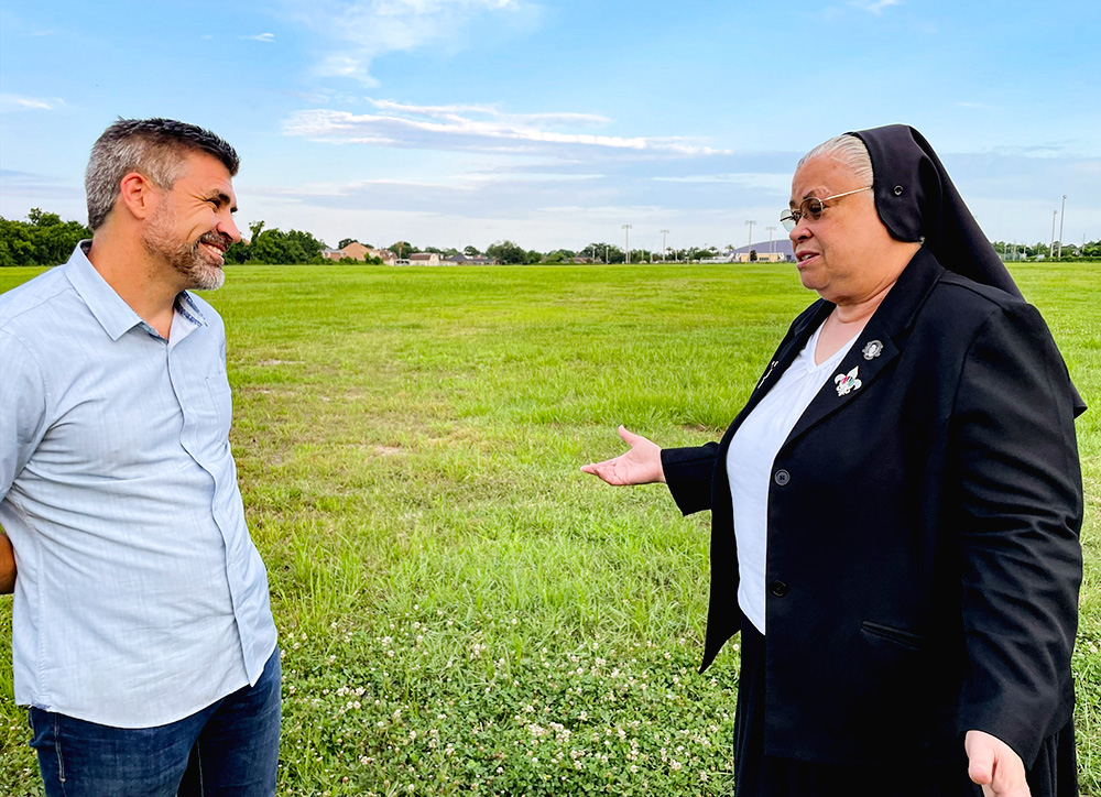 Broderick Bagert, a Together New Orleans organizer, listens to Sr. Alicia Costa, superior of the Sisters of the Holy Family, with the sisters' land designated for the solar field in the background. In the far background is St. Mary's Academy. (Kevin Fitzpatrick)