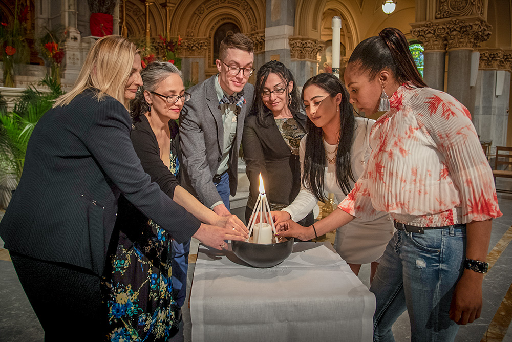 Graduates of Xavier Mission's Life Skills Empowerment Programs, or LSEP, take part in a candle-lighting ceremony at St. Francis Xavier Church in New York City in May 2018. The ceremony is intended to signify the community of the participants in the program, as individuals joining together in one unit. (John Langdon)