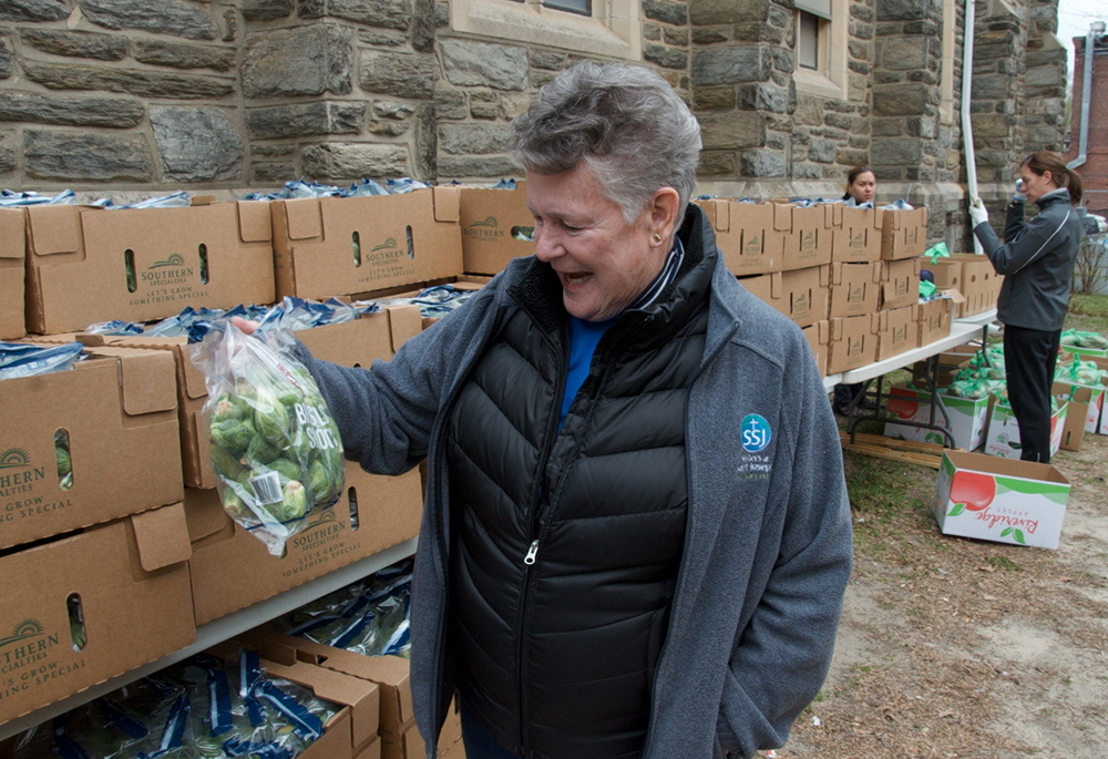 Sr. Bonnie McMenamin, a Sister of St. Joseph of Philadelphia and director of the SSJ Neighborhood Center in Camden, New Jersey, shows the bags of Brussels sprouts the center is preparing to hand out as part of its monthly food distribution day, March 20. (GSR photo/Dan Stockman)
