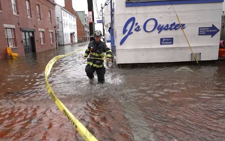 First responder wades through knee-deep water in street