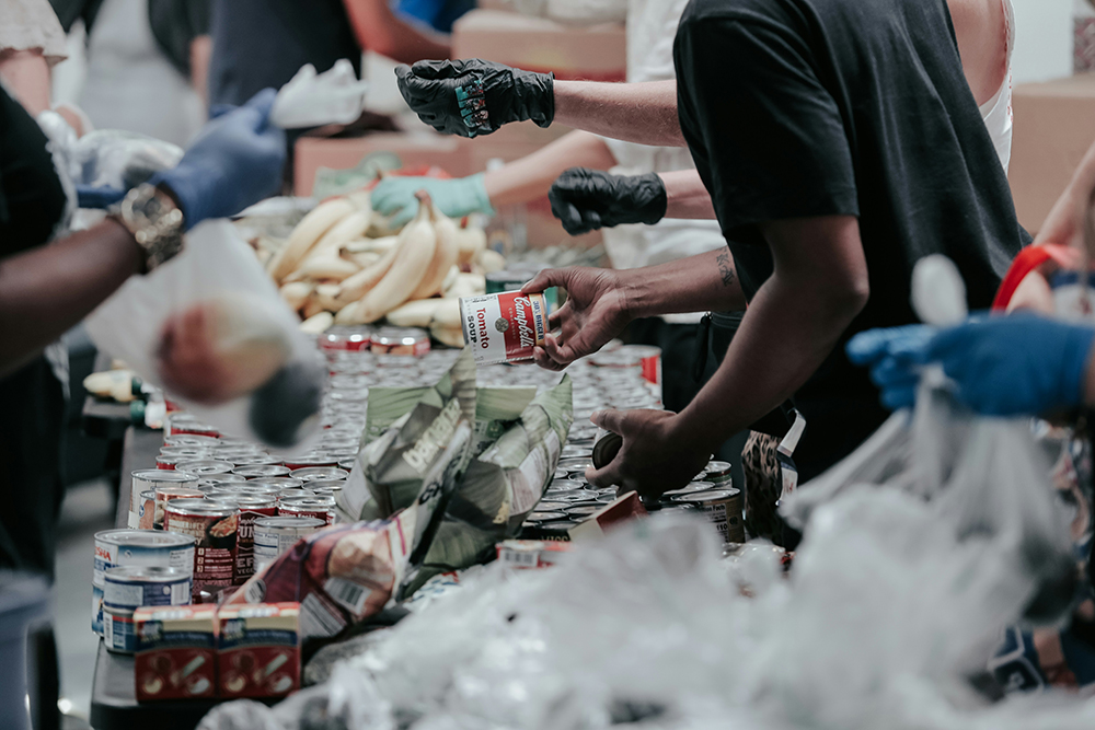 A line of people hand out food (Unsplash/Joel Muniz)