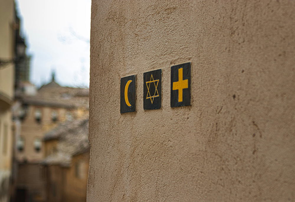 Black and yellow religion symbols are pictured adorning an outside wall. (Unsplash/Noah Holm)