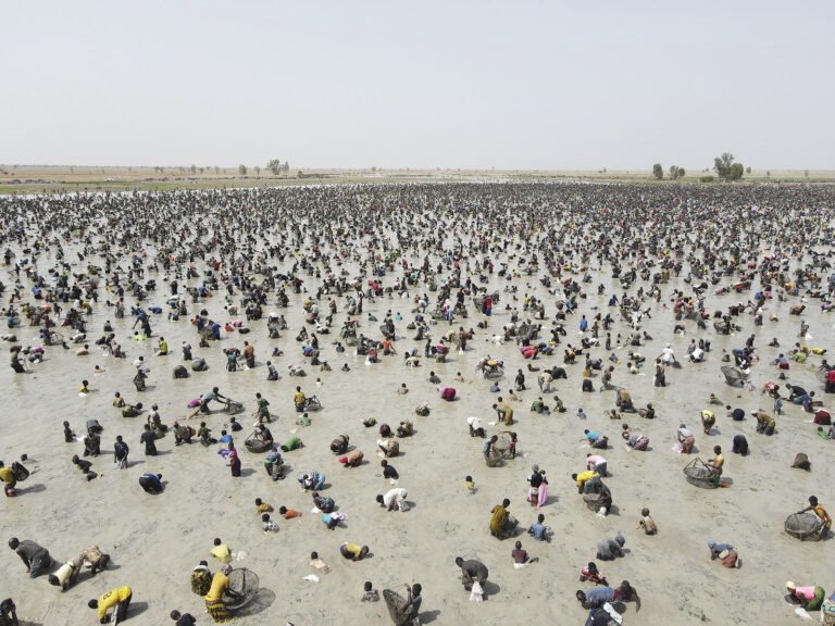 Wide view of a desiccated pond filled with people