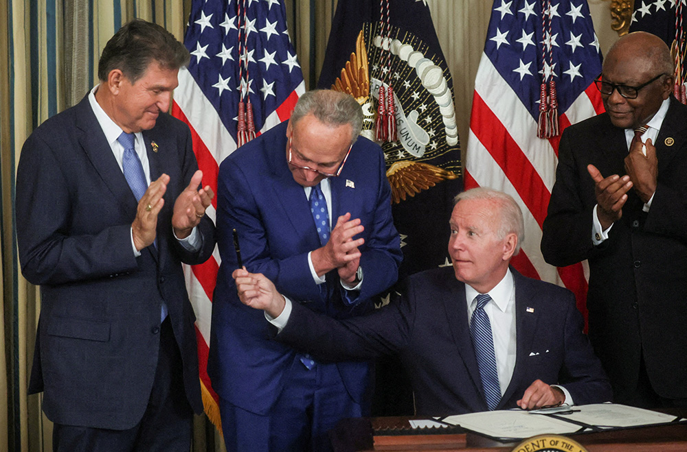 President Joe Biden holds out his pen to Sen. Joe Manchin, D-West Virginia, as Senate Majority Leader Chuck Schumer, D-New York, and then-House Majority Whip James Clyburn, D-South Carolina, look on in the State Dining Room of the White House in Washington Aug. 16, 2022, after Biden signed the Inflation Reduction Act of 2022 into law. (CNS/Reuters/Leah Millis)