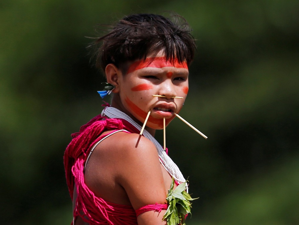 Pierced and painted girl in traditional garb looks at camera. 