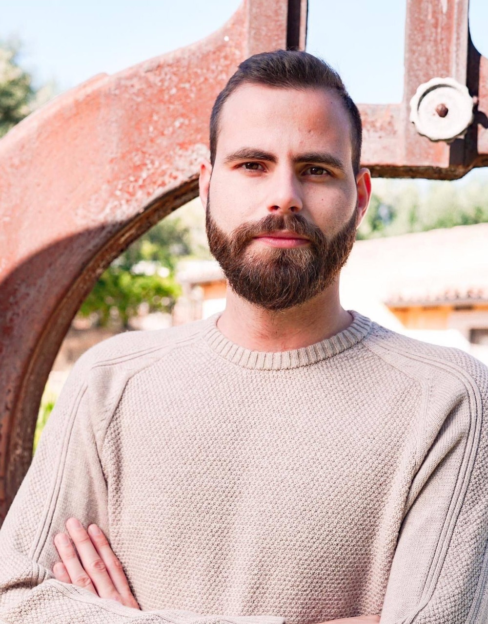 Outdoor, natural-lit headshot of Messina, arms folded, looking at camera. 