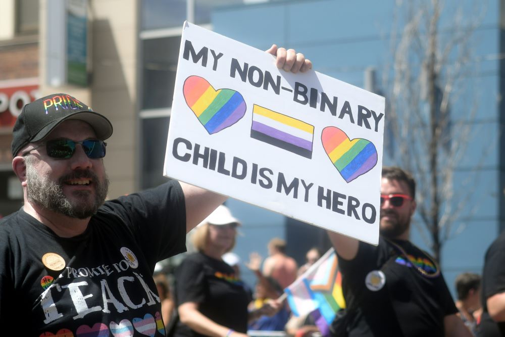 Man holds sign: "My nonbinary child is my hero."