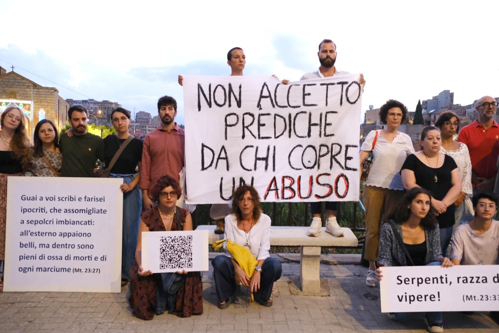 The ensemble poses, holding Italian-language signs. 