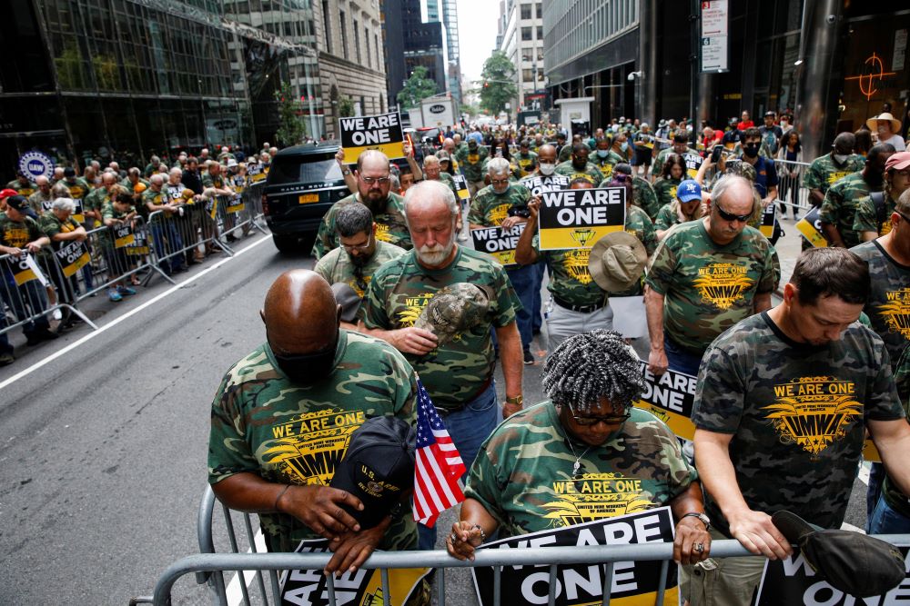 Labor leaders bow in prayer while picketing July 28, 2021, outside BlackRock's headquarters in New York City. 