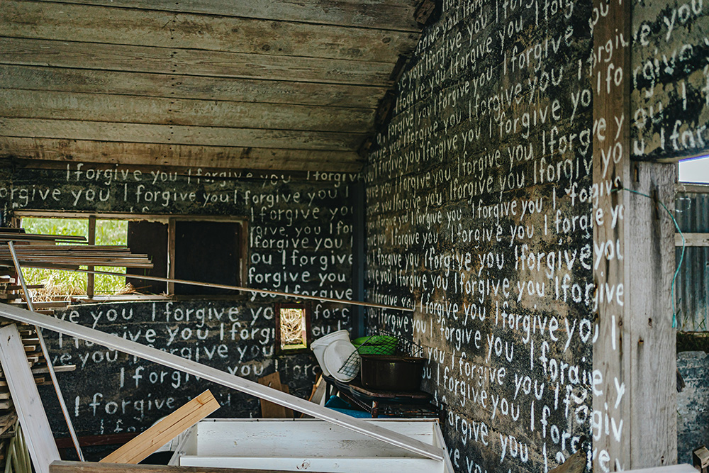 An abandoned room painted with I forgive you in white paint (Unsplash/Bailey Burton)