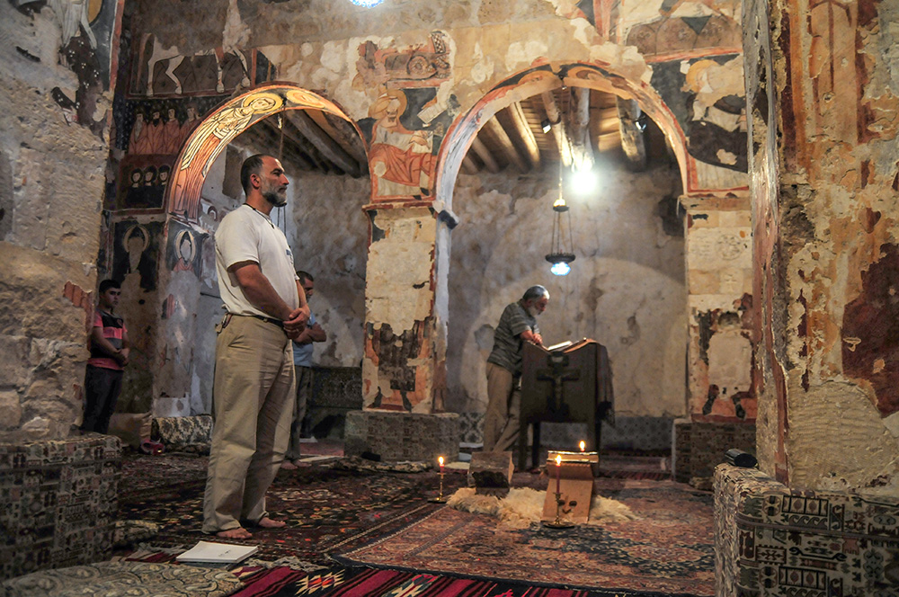 Syriac Catholic Fr. Jihad Youssef prays inside the church of Mar Musa Monastery in Syria in June 2017. Youssef became head of the monastic community in 2021. (Newscom/picture-alliance/dpa/Simon Kremer)